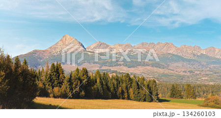 Autumn meadows near country road, panorama of Tatry mountains with Krivak peak (Slovak symbol) as seen from Vazec village in distance 134260103
