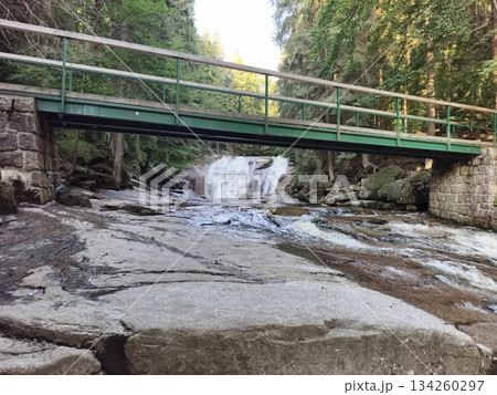 walkway crossing stony riverbed scene, bridge spanning rugged stream with waterfalls and textures 134260297