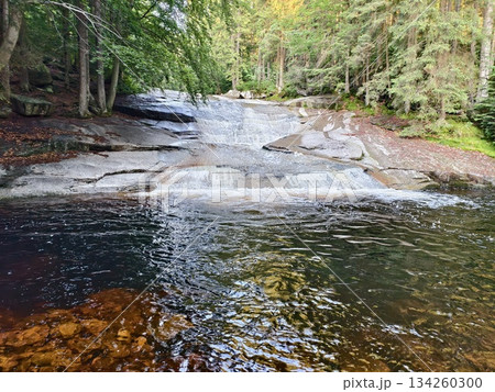 tranquil waterway with stones, idyllic freshwater setting with reflective waters and gentle ripples tranquil waterway with stones, idyllic freshwater setting with reflective waters and gentle ripples 134260300