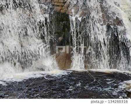 rapid water splashing over rocks, vigorous waterfall unleashing frothy white torrents on rugged rocks rapid water splashing over rocks, vigorous waterfall unleashing frothy white torrents on rugged rocks 134260316