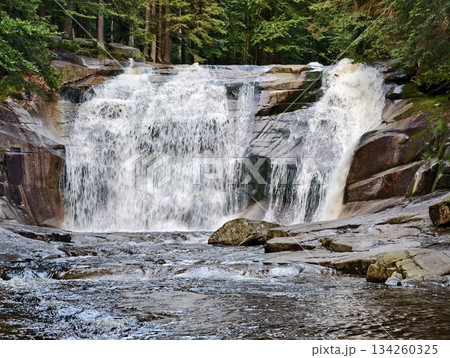 swirling currents in serene river landscape, calm rapids with textured stones and vibrant flowing water 134260325