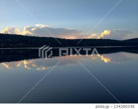calm waters mirror vibrant sky colors, tranquil reflection of sunset with peaceful surrounding landscape 134260336
