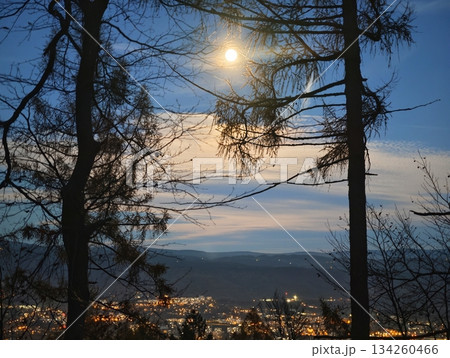 urban horizon illuminated by setting sun, mountain silhouettes frame vibrant city skyline at dusk 134260466