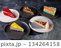 Assorted Cake Slices On Dark Slate Plates Create Colorful Dessert Display For Party 134264158