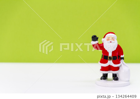 明るい黄緑色の背景に立つサンタクロースのフィギュア　 クリスマスイメージ 134264409