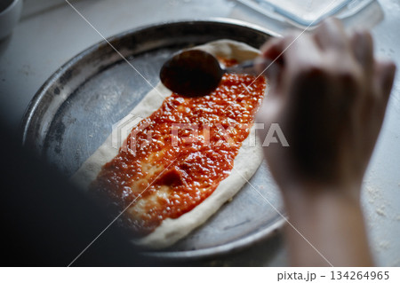 Spreading tomato sauce on pizza pan Spreading tomato sauce on pizza pan 134264965