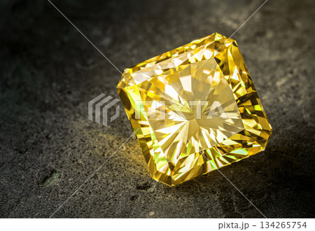 A yellow diamond is sitting on a grey surface 134265754