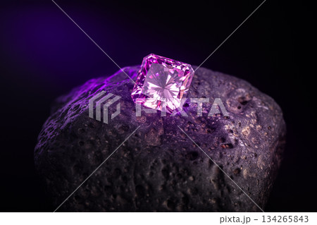 A small pink diamond is sitting on a rock 134265843