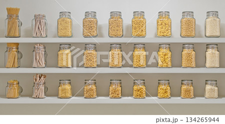 A shelf full of glass jars with different colored pasta A shelf full of glass jars with different colored pasta 134265944