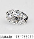 A white oval cut diamond is sitting on a white surface 134265954