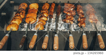 A grill with skewers of meat and potatoes on it A grill with skewers of meat and potatoes on it 134265960