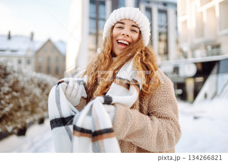 Portrait woman with mittens in a knitted hat and sheepskin coat outside in the city park in winter. Portrait woman with mittens in a knitted hat and sheepskin coat outside in the city park in winter. 134266821