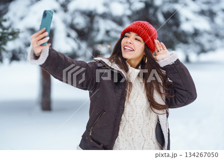 Young woman taking selfie in winter forest. Holidays, rest, travel concept. Young woman taking selfie in winter forest. Holidays, rest, travel concept. 134267050