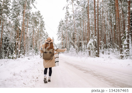Beautiful young woman in winter forest is waiting for a car. Hitchhiking in winter. Great snowy day. 134267465