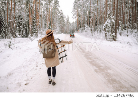 Beautiful young woman in winter forest is waiting for a car. Hitchhiking in winter. Great snowy day. Beautiful young woman in winter forest is waiting for a car. Hitchhiking in winter. Great snowy day. 134267466