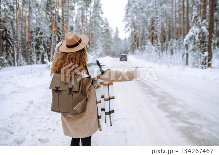 Beautiful young woman in winter forest is waiting for a car. Hitchhiking in winter. Great snowy day. Beautiful young woman in winter forest is waiting for a car. Hitchhiking in winter. Great snowy day. 134267467