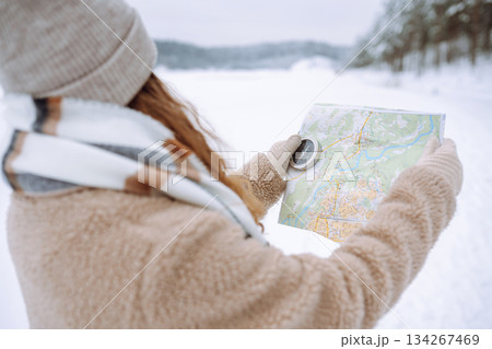 Beautiful woman traveler holds a compass and map in hands. Enjoying winter travel. Active lifestyle. Beautiful woman traveler holds a compass and map in hands. Enjoying winter travel. Active lifestyle. 134267469