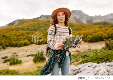 Young woman hiking in autumn landscape with a map. Travel, nature concept. Active lifestyle. 134267822