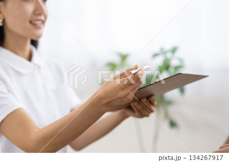 白衣を着た女性が手に持つバインダーとペンのクローズアップ 白衣を着た女性が手に持つバインダーとペンのクローズアップ 134267917