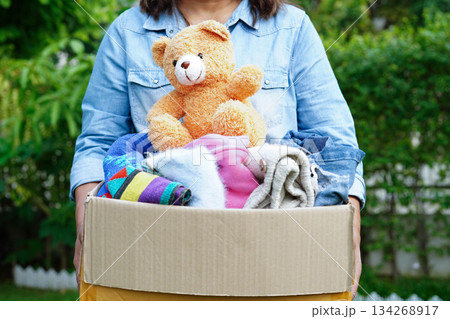 Volunteer collect cloth and doll in cardboard box to donate. Volunteer collect cloth and doll in cardboard box to donate. 134268917