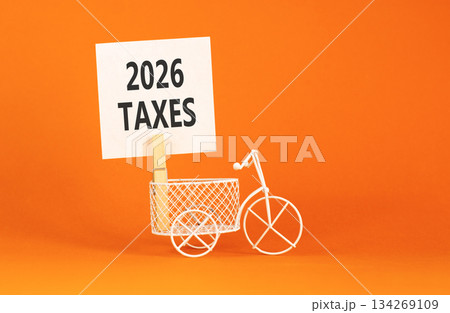 2026 taxes symbol. Concept words 2026 taxes on beautiful white paper on wooden clothespin. Beautiful orange background. Beautiful miniature bicycle. Business 2026 taxes new year concept. Copy space. 134269109