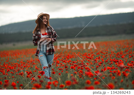 Woman walking poppy field holds flowers enjoys freedom copy space 134269243