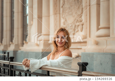 Woman, Smiling, Fence - Blonde woman smiles while leaning on a black fence in front of a building. 134269316