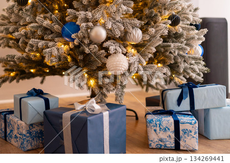 Christmas tree wrapped gifts holiday celebration under snowy festive fir branches at home Christmas tree wrapped gifts holiday celebration under snowy festive fir branches at home 134269441