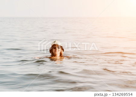 Woman, Ocean, Swimming - A woman wearing a white bucket hat swims in the ocean. 134269554