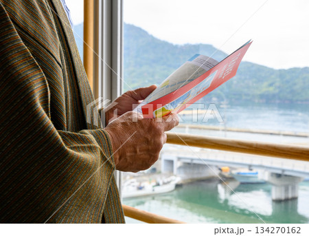 窓辺で観光パンフレットを読むシニア 134270162