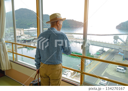 窓から港を眺める初老の男性 134270167