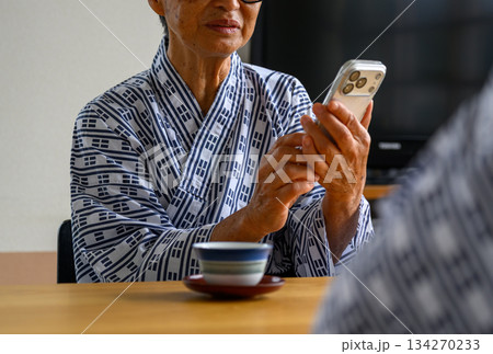 浴衣姿のシニアがスマホを操作 浴衣姿のシニアがスマホを操作 134270233
