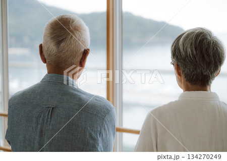 窓から海を眺める老夫婦の後ろ姿 134270249