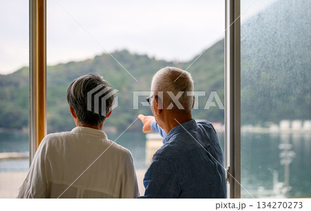 窓から海と山を眺める老夫婦 134270273