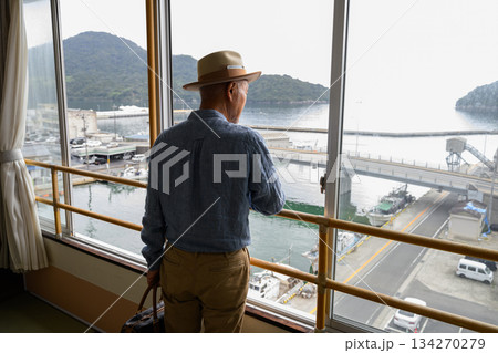 窓から港を眺める旅行中のシニア男性 134270279