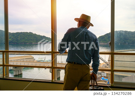 窓から海と島を眺める紳士 134270286