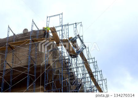 Workers on scaffolding repair building in construction area 134270314