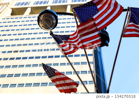 American flags wave on pole in New York city with tall buildings 134270318