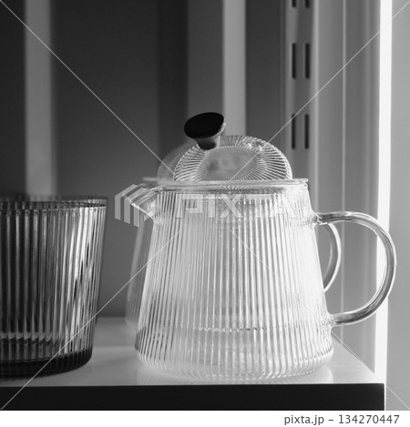 Traditional glass teacup and teapots with chrome handles in the night kitchen. Clean glass kitchenware for evening tea square stock photo  134270447