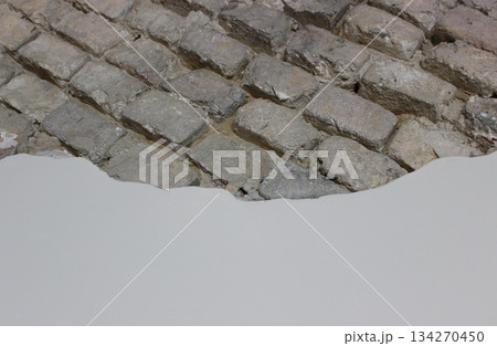 An even layer of wall finishing gradually covers the old brick wall. Old wall structure and repair technology  134270450