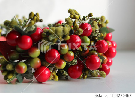 Part Of Wreath With Artificial Colored Berries And Textile Leaves On White Background Closeup Side View Part Of Wreath With Artificial Colored Berries And Textile Leaves On White Background Closeup Side View 134270467