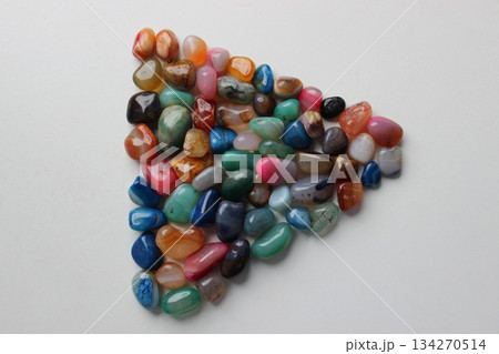 Triangle laid out from colored decorative stone crystals on a white surface 134270514