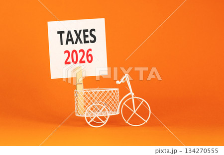 Taxes 2026 symbol. Concept words Taxes 2026 on beautiful white paper on wooden clothespin. Beautiful orange background. Beautiful miniature bicycle. Business taxes 2026 new year concept. Copy space. Taxes 2026 symbol. Concept words Taxes 2026 on beautiful white paper on wooden clothespin. Beautiful orange background. Beautiful miniature bicycle. Business taxes 2026 new year concept. Copy space. 134270555