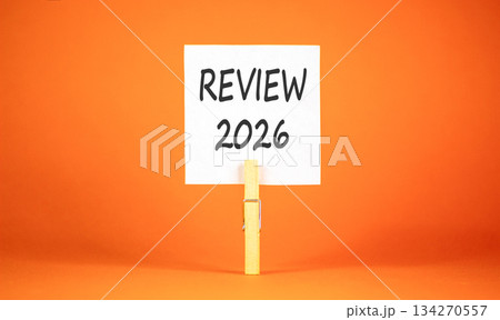 Review 2026 symbol. Concept words Review 2026 on beautiful white paper on wooden clothespin. Beautiful orange background. Business and review 2026 concept. Copy space. 134270557