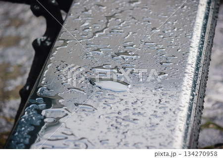 Close up of a dark, wet table surface covered in water puddles and rain with abstract patterns 134270958