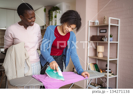Mother and Daughter Ironing Clothes Together at Home 134271138