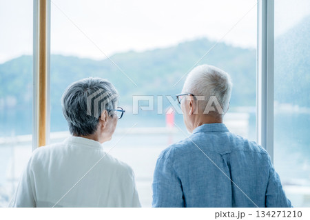 窓から海と山を眺める老夫婦 134271210