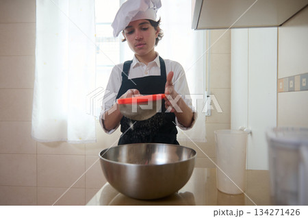 Young Student Chef Sifts Flour In Bright Kitchen, Focused On Batter Preparation 134271426