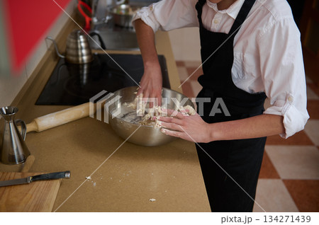 Chef In White Shirt And Black Apron Mixing Dough In Stainless Bowl In Kitchen Chef In White Shirt And Black Apron Mixing Dough In Stainless Bowl In Kitchen 134271439
