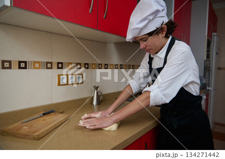 Chef In White Shirt And Black Apron Kneading Dough In Modern Red Kitchen 134271442